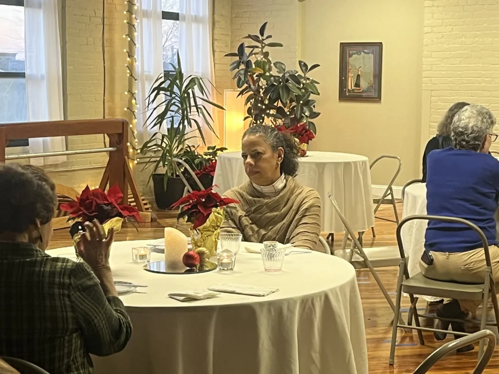 Community members gathered around decorated tables at the studio holiday gathering